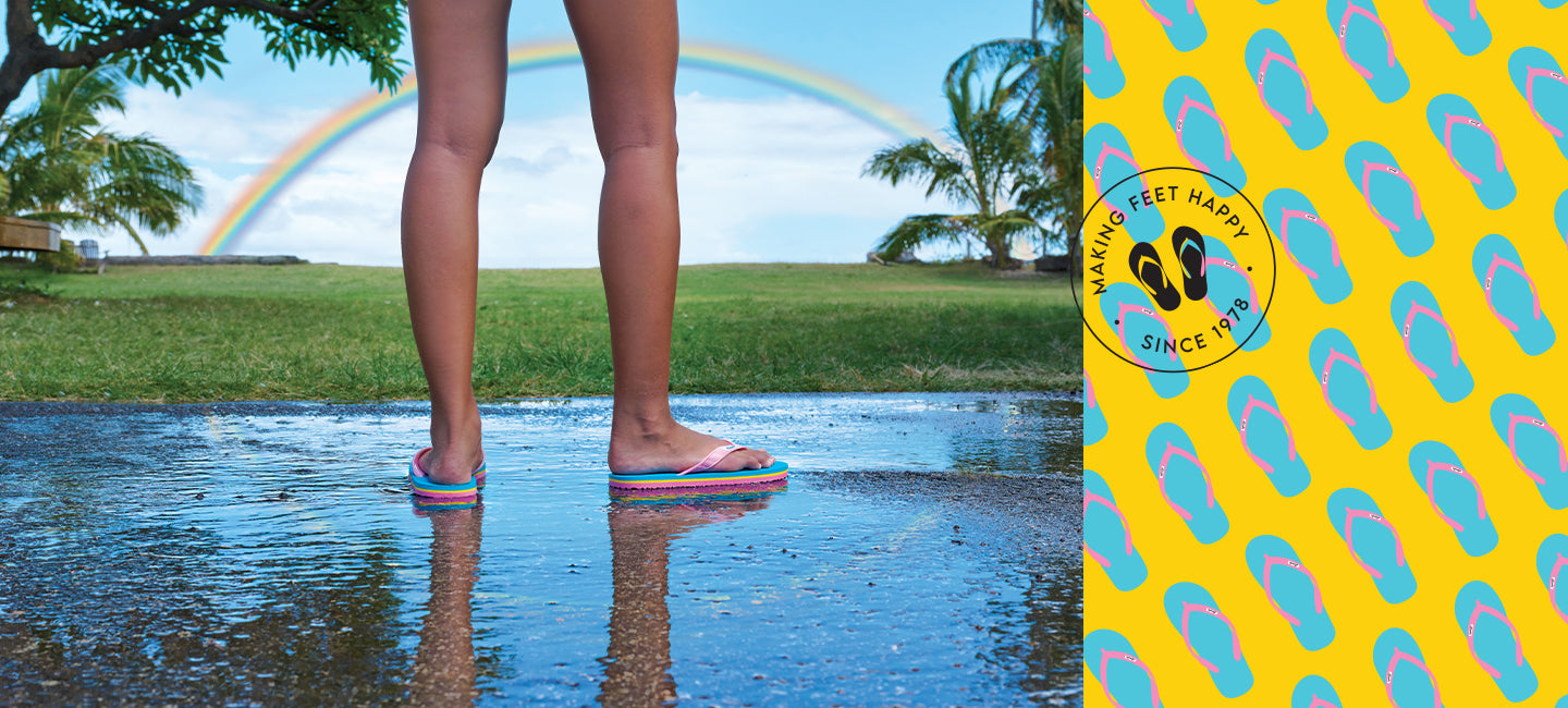 Closeup of child wearing Locals slippahs with a rainbow in the background